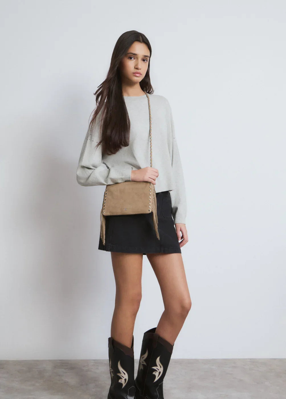 אאוטפיט אופנתי לנשים של CHOZEN: חצאית שחורה, סווטשירט אפור, תיק צד בז' ומגפיים בולטים