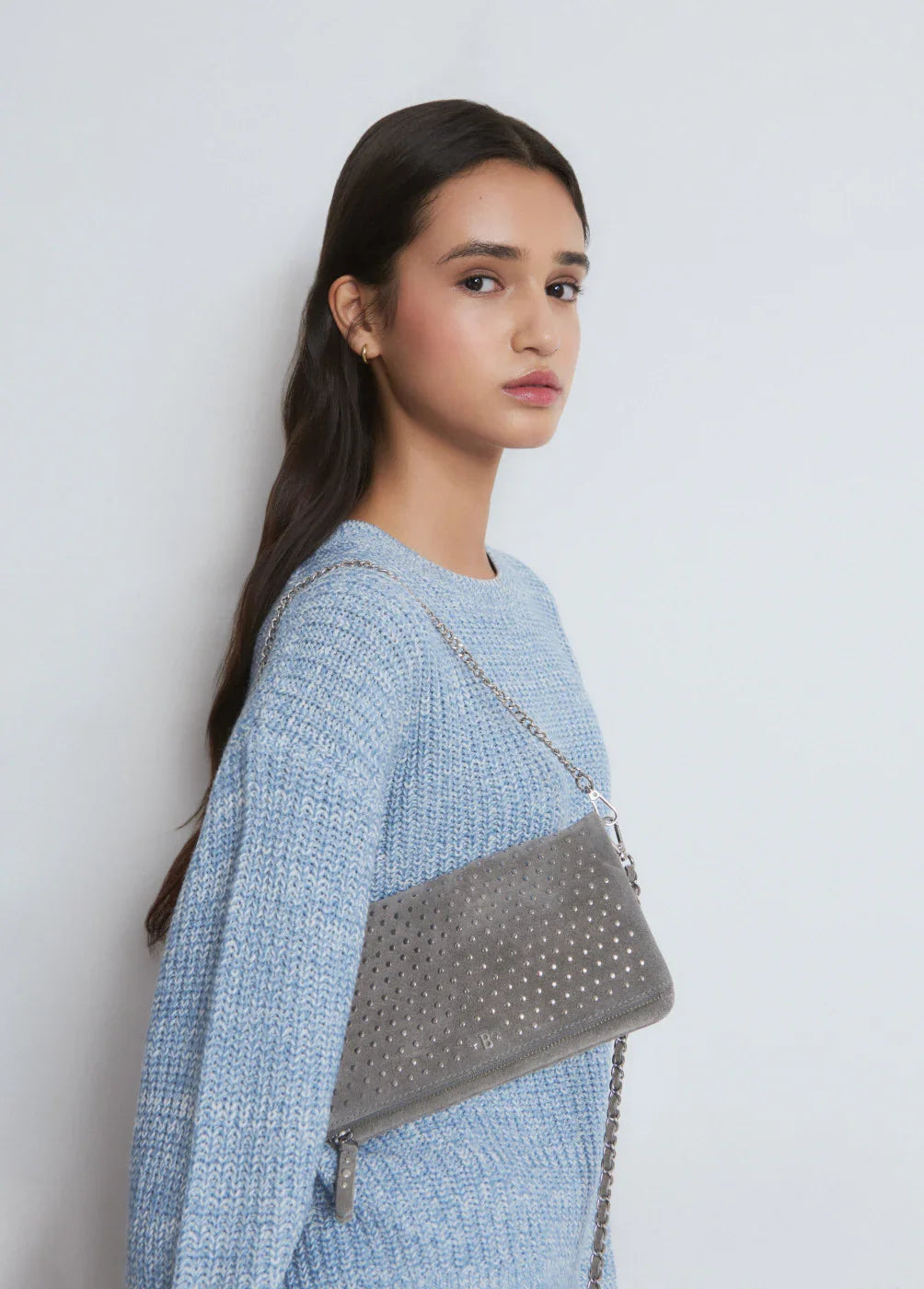 אישה עם סוודר תכלת ותיק צד אפור עם ניטים, צולם עבור CHOZEN מותגים מובילים