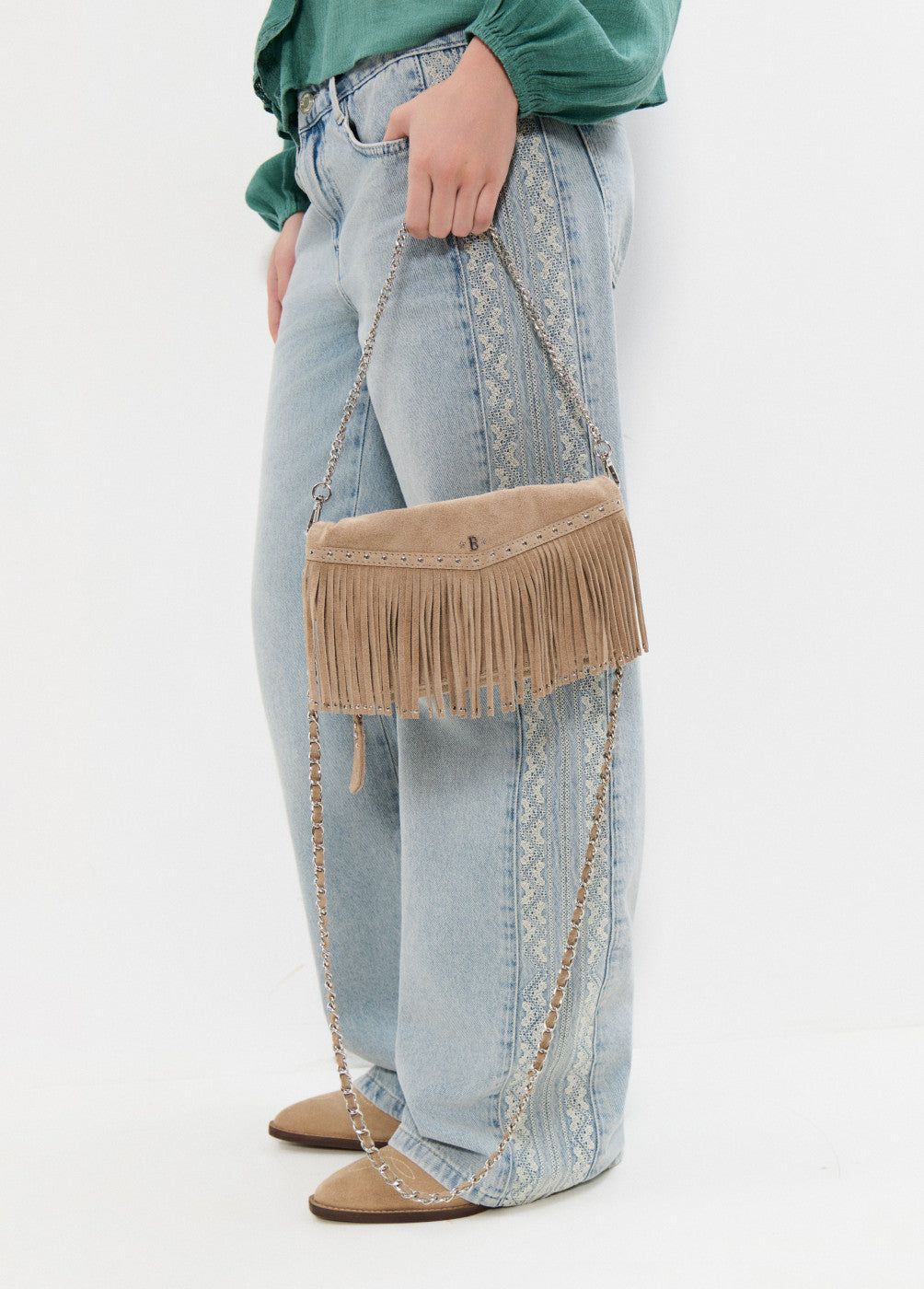 תיק קז'ואל עשוי זמש בצבע בז', עם פרנזים ושרשרת כסף, משולב עם ג'ינס רחב והדפס