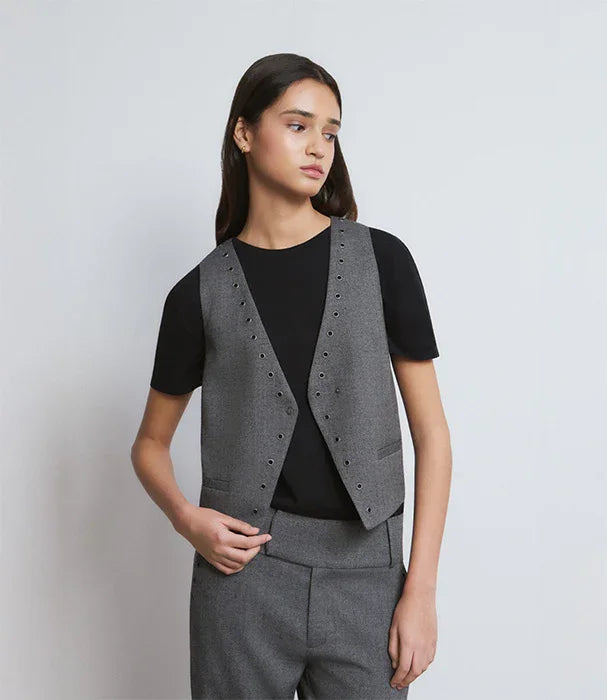 אישה לובשת וסט מחויט אפור ומכנסיים תואמים, חולצה שחורה, אופנה אלגנטית לנשים