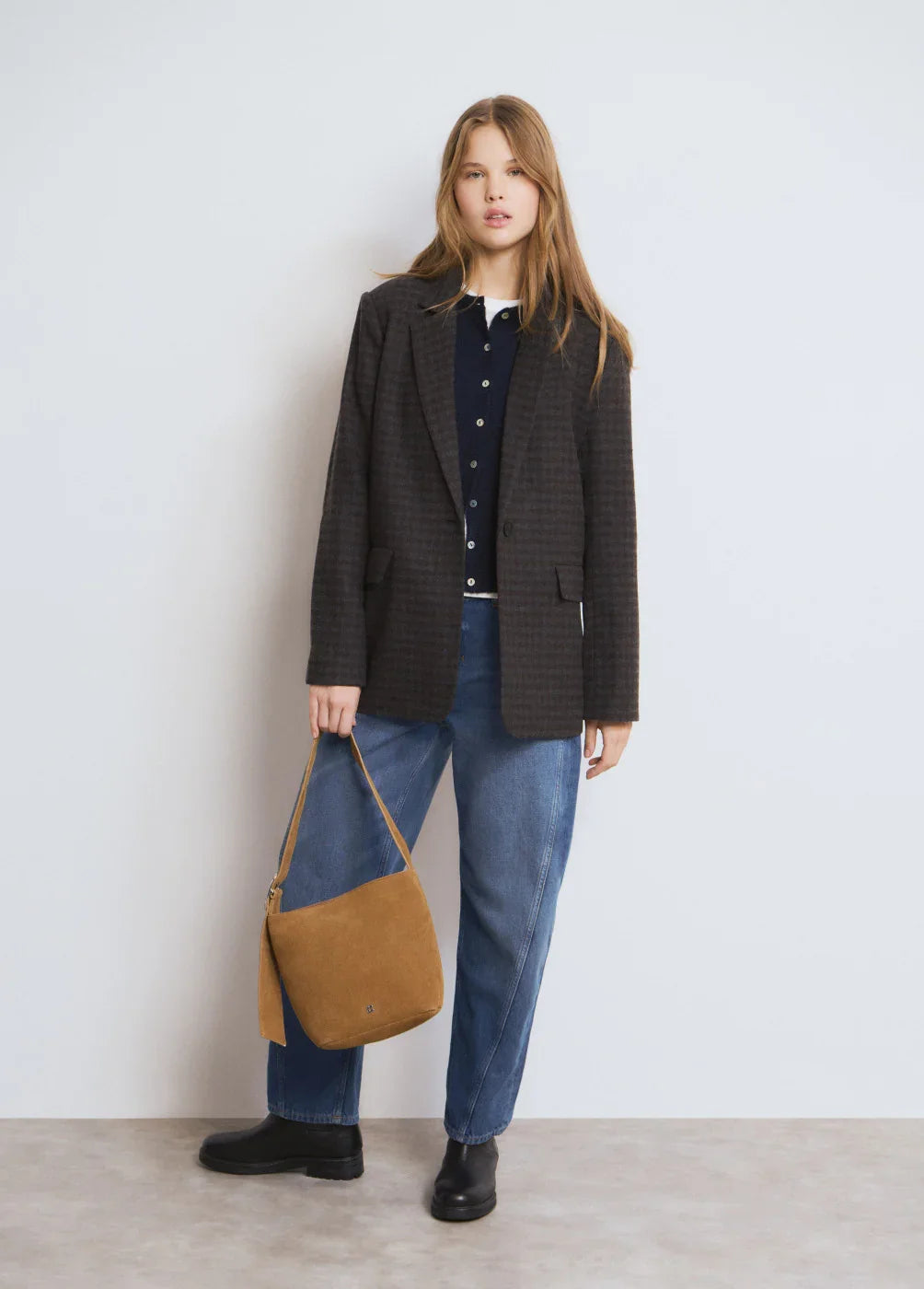 אופנת נשים CHOZEN, דוגמנית עם בלייזר כהה, ג'ינס רחב, תיק חום ונעלי מגף שחורות