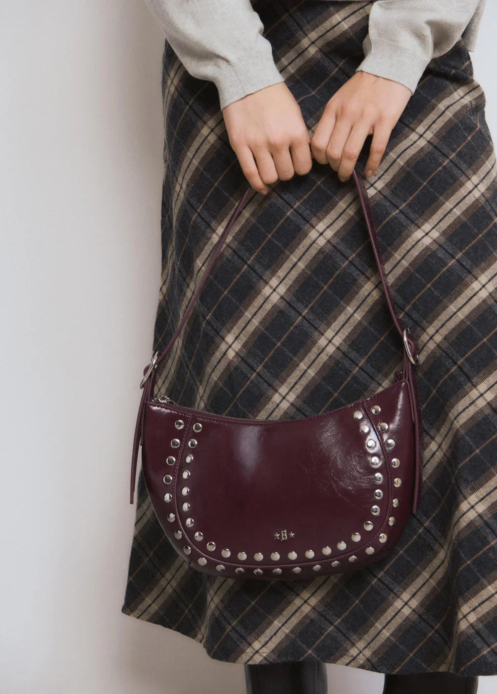 תיק כתף סגול עם ניטים כסופים, אופנת נשים CHOZEN, קבוצת אלפא, על רקע חצאית משובצת