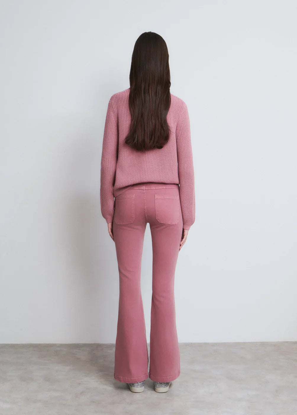 אישה עם שיער ארוך לובשת סוודר ומכנסיים ורודים, צילום אחורי, CHOZEN אופנה