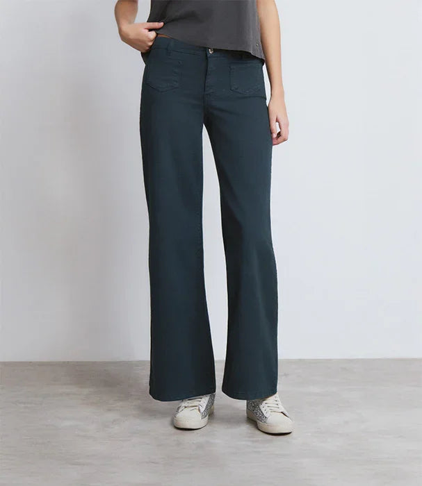 מכנסי נשים בגזרה רחבה בצבע כחול כהה, עם שני כיסים קדמיים, חולצה אפורה ונעלי סניקרס