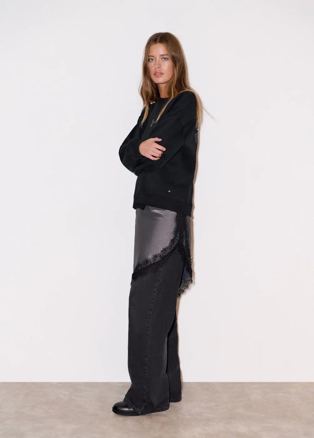 אישה מדגמנת בגדי אופנה שחורים CHOZEN, חולצה שחורה ומכנסיים כהים, רקע לבן חלק