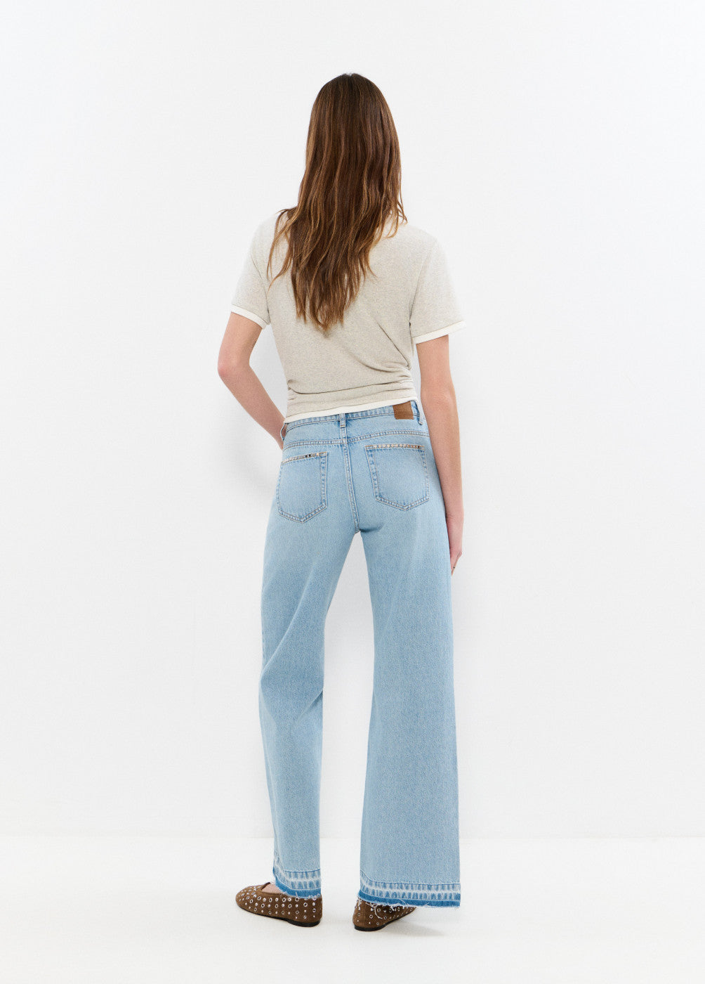 ג'ינס רחב בגזרה גבוהה בצבע תכלת לנשים, מבט מאחור על דוגמנית עם חולצה בהירה