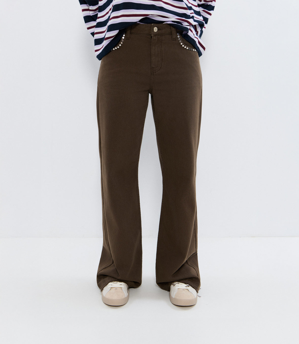 מכנסיים חומים עם גזרה ישרה, קישוט ניטים בכיסים, נעלי סניקרס לבנות