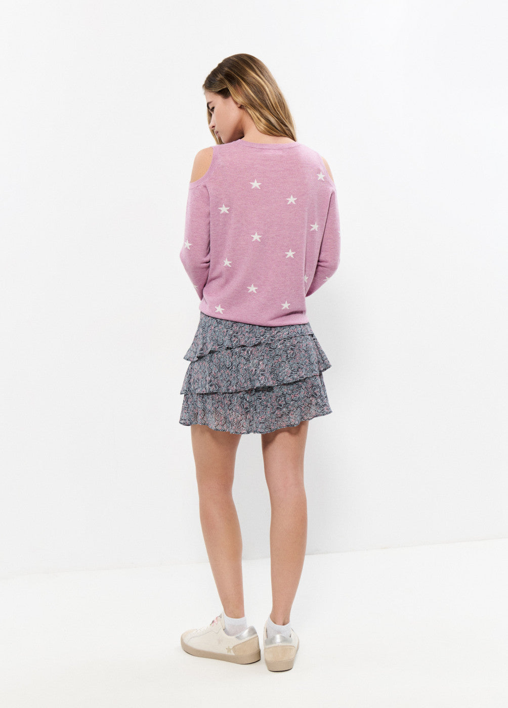 אישה עם סווטשרט ורוד עם כוכבים וחצאית קומות פרחונית, מבט מאחור, אופנת נשים אביבית