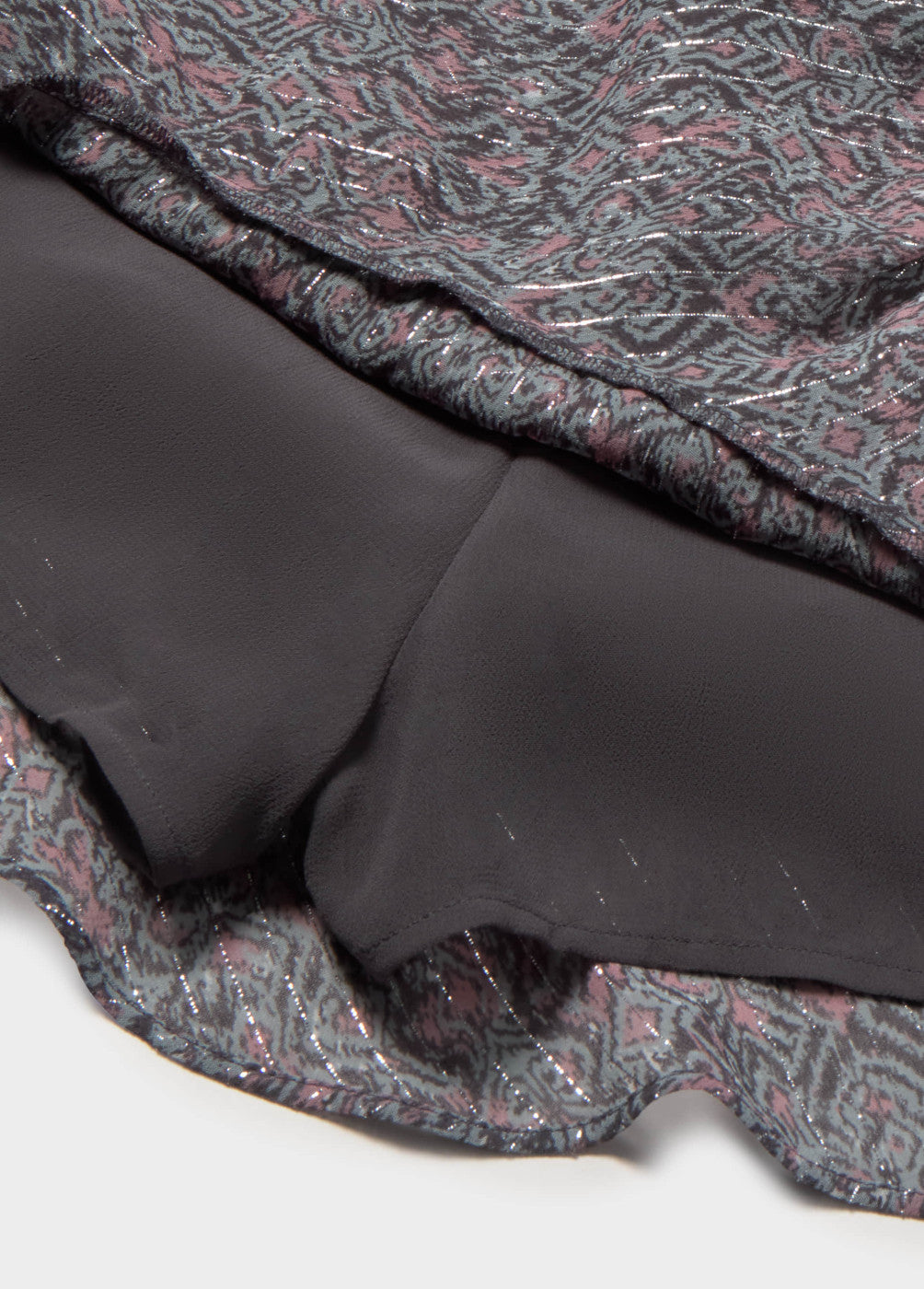 תקריב בד חצאית עם בטנה שחורה ודוגמה פרחונית מנצנצת בגווני סגול וכסף