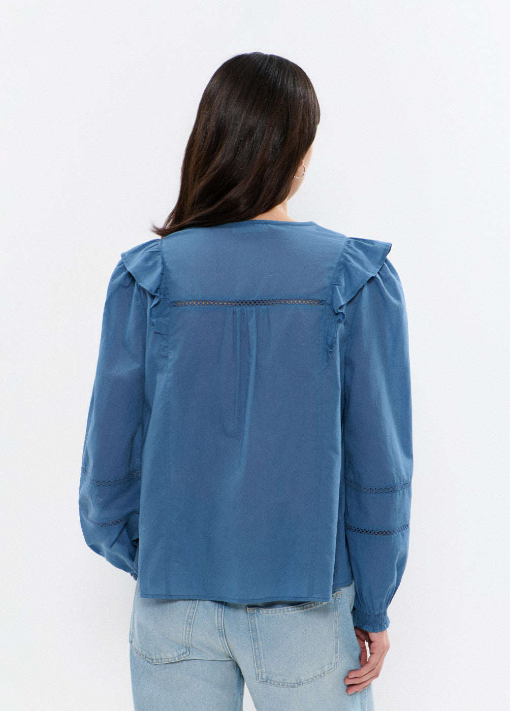 חולצה כחולה לנשים עם שרוולים ארוכים ופרטים מעוטרים, מבט מאחור, ג'ינס בהיר