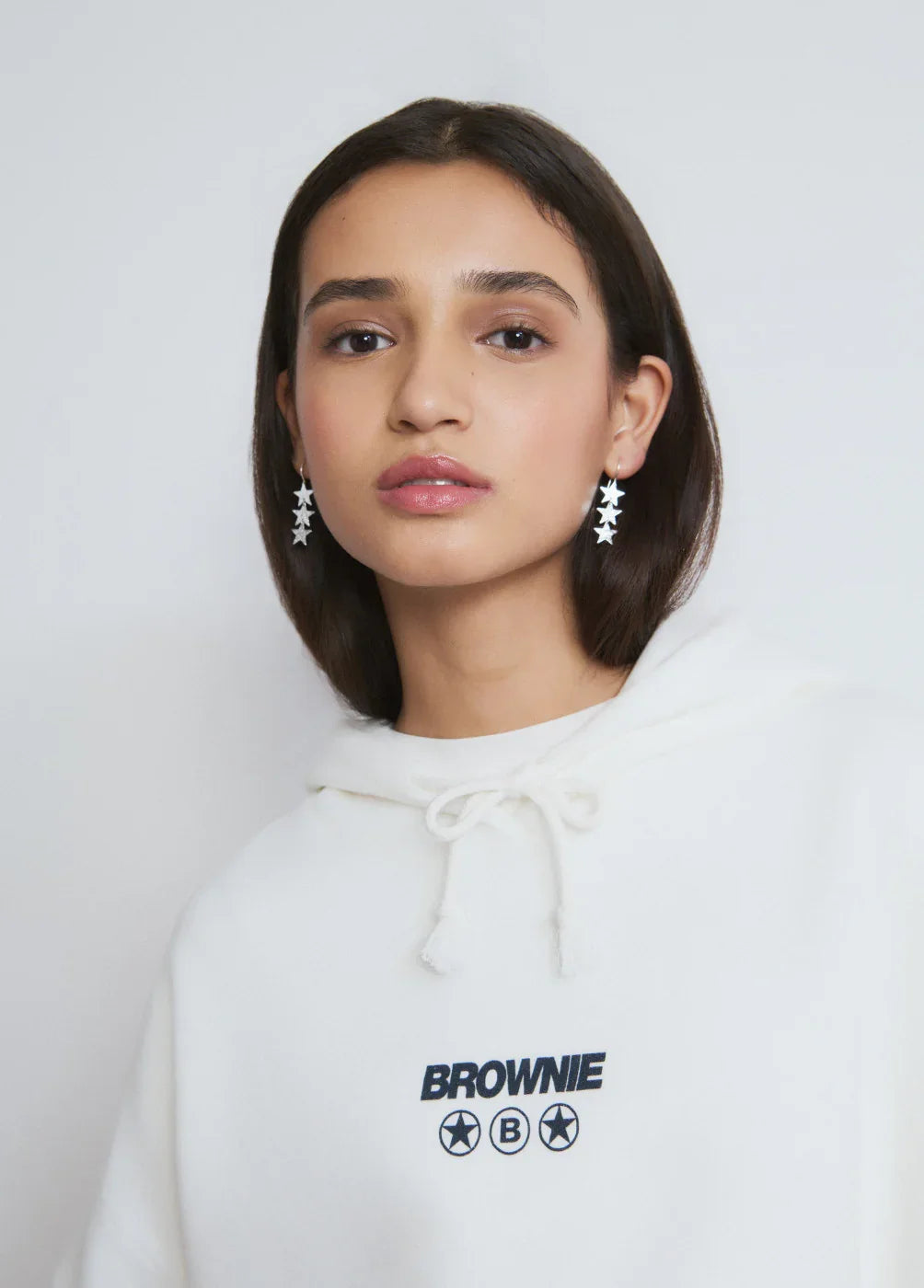 אישה צעירה לובשת קפוצ'ון לבן של BROWNIE ועגילי כוכבים, צילום אופנה ל-CHOZEN