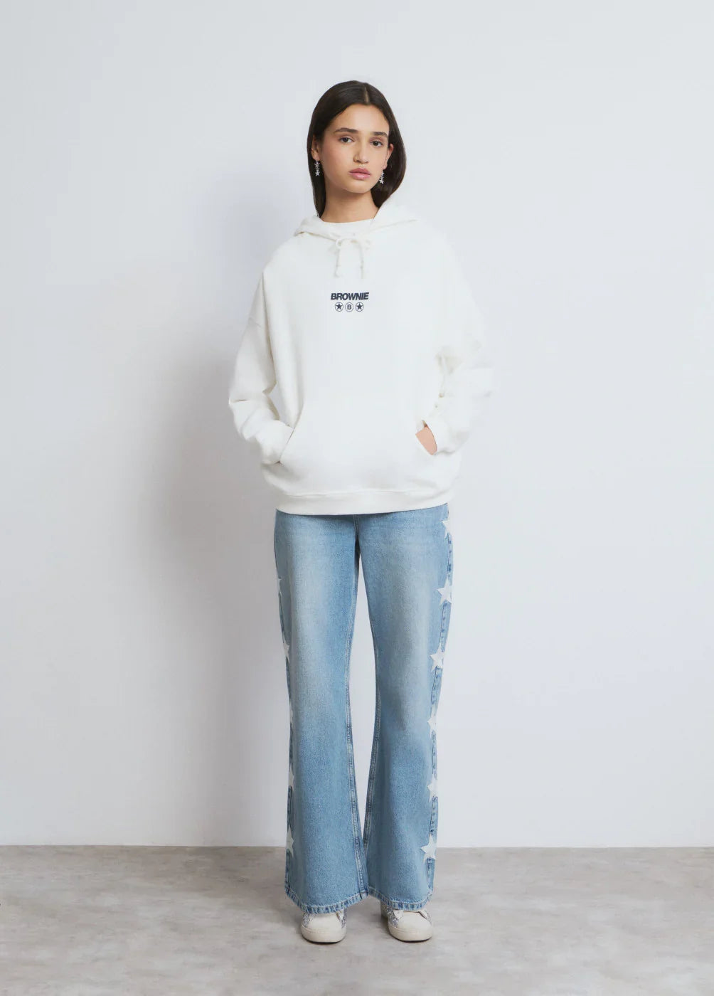 דוגמנית לובשת קפוצ'ון לבן עם כיתוב BROWNIE ומכנסי ג'ינס כחולים עם כוכבים, אופנת נשים CHOZEN