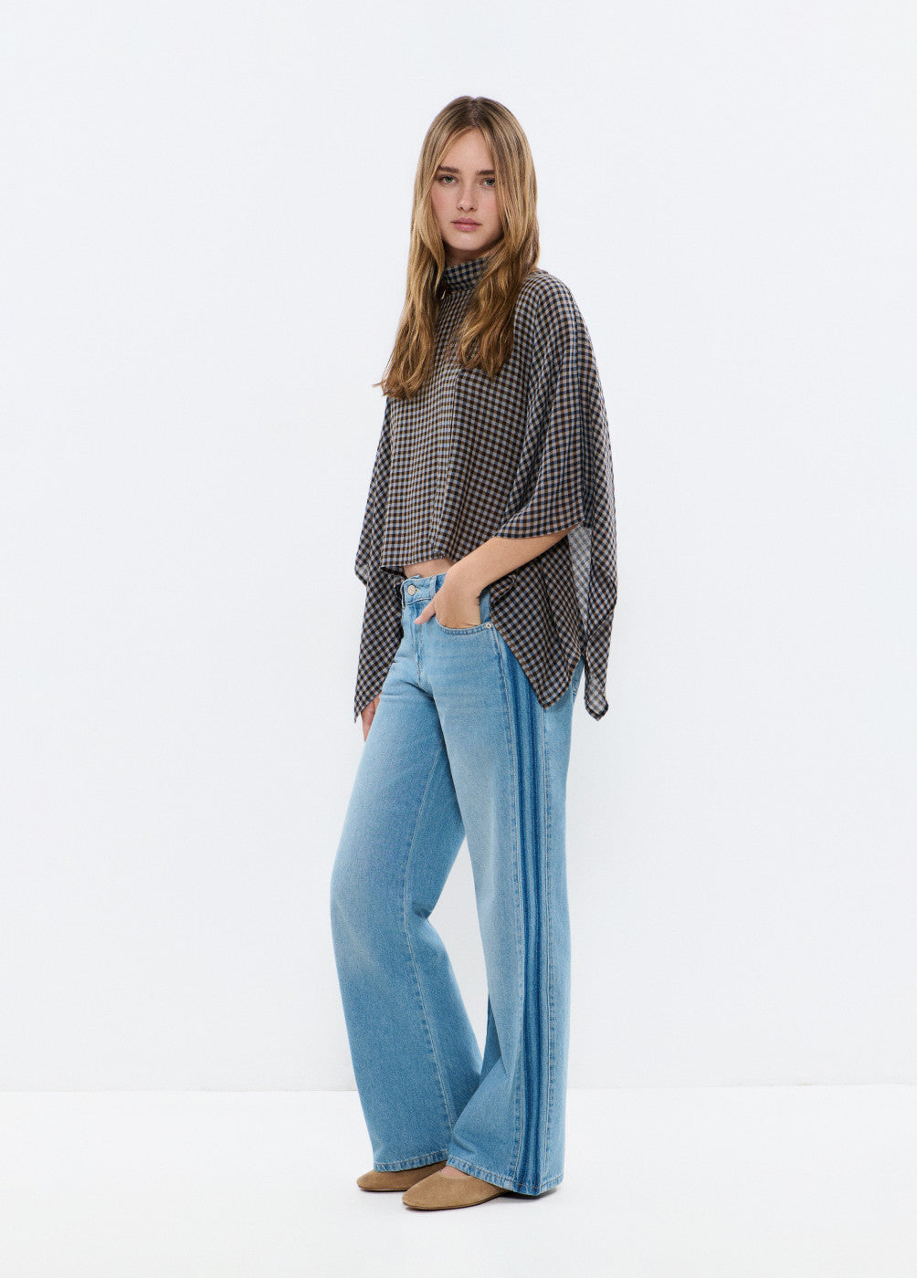 אישה לובשת חולצת משבצות רחבה ומכנסי ג'ינס בגזרה רחבה, אופנת נשים עדכנית