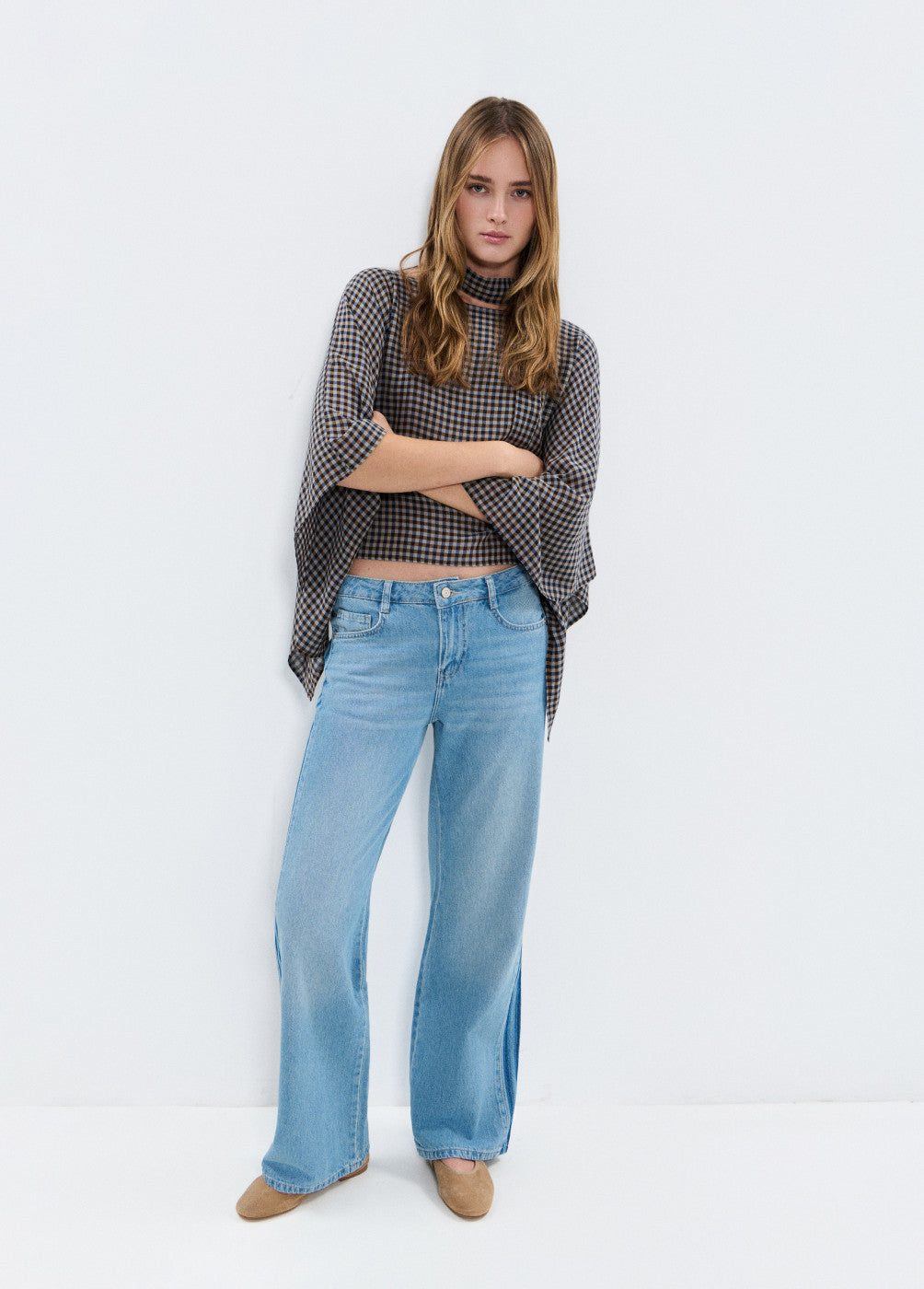 דוגמנית לובשת ג׳ינס רחב עם חולצת קרופ משובצת שרוולים רחבים, אופנת נשים עדכנית