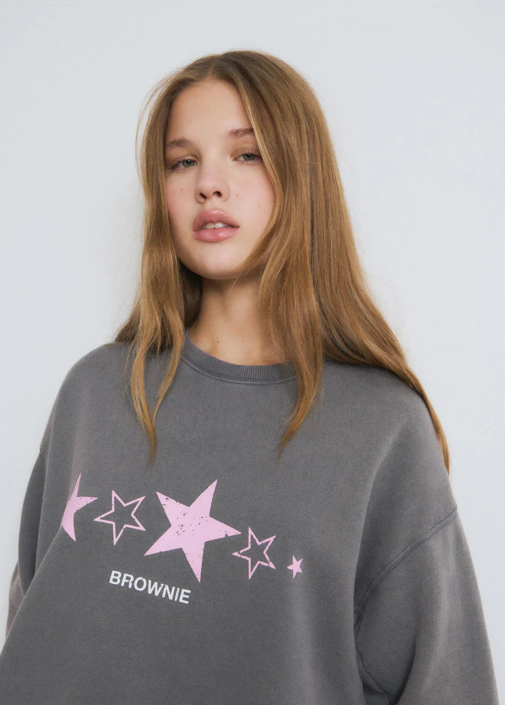 דוגמנית בחולצת סווטשירט אפורה עם כוכבים ורודים וכיתוב BROWNIE, אופנה ב-CHOZEN