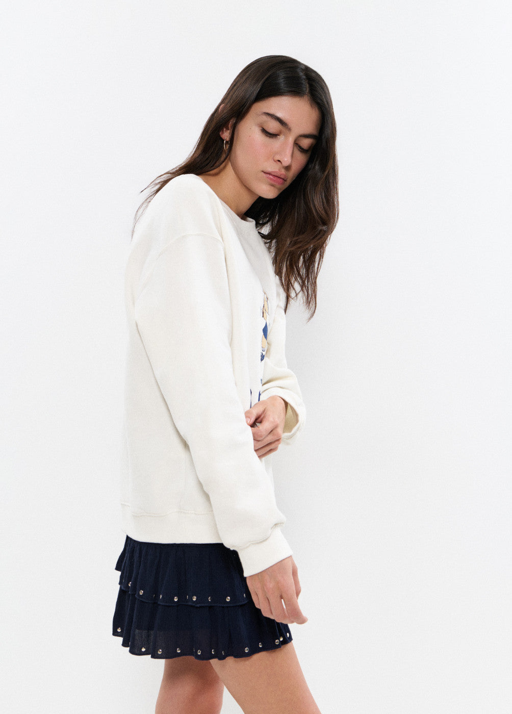 אישה עם סווטשירט לבן וחצאית שחורה קצרה בשכבות, רקע לבן, אופנה נשית