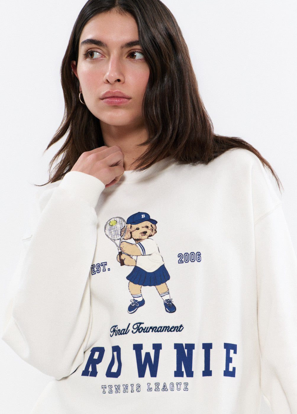 דוגמנית לובשת סווטשירט לבן עם הדפס כלב משחק טניס וטקסט כחול, אופנת נשים
