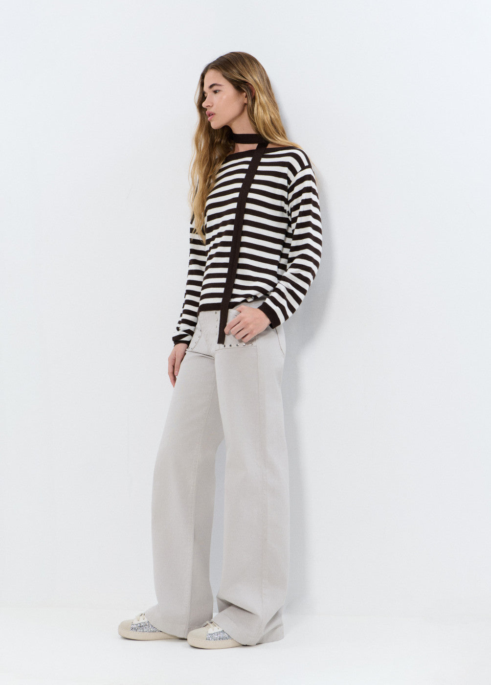 אישה עם סוודר פסים שחור לבן ומכנסיים רחבים לבנים, אופנה מודרנית קז'ואל