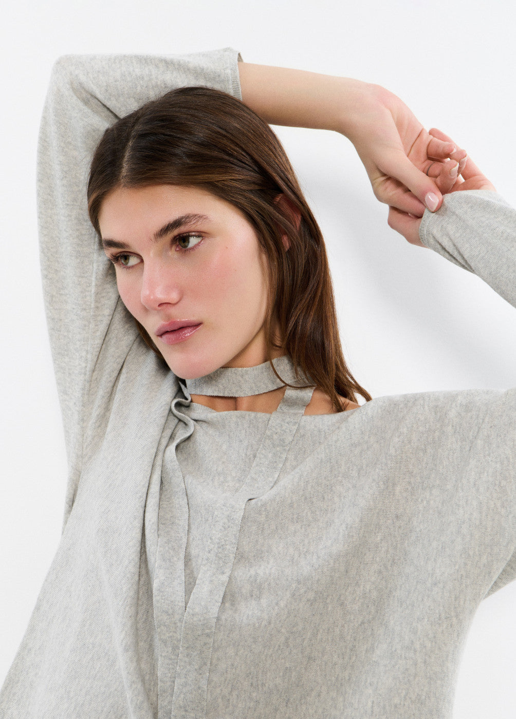דוגמנית לובשת סוודר אפור בעיצוב פשוט עם קשירה בצוואר
