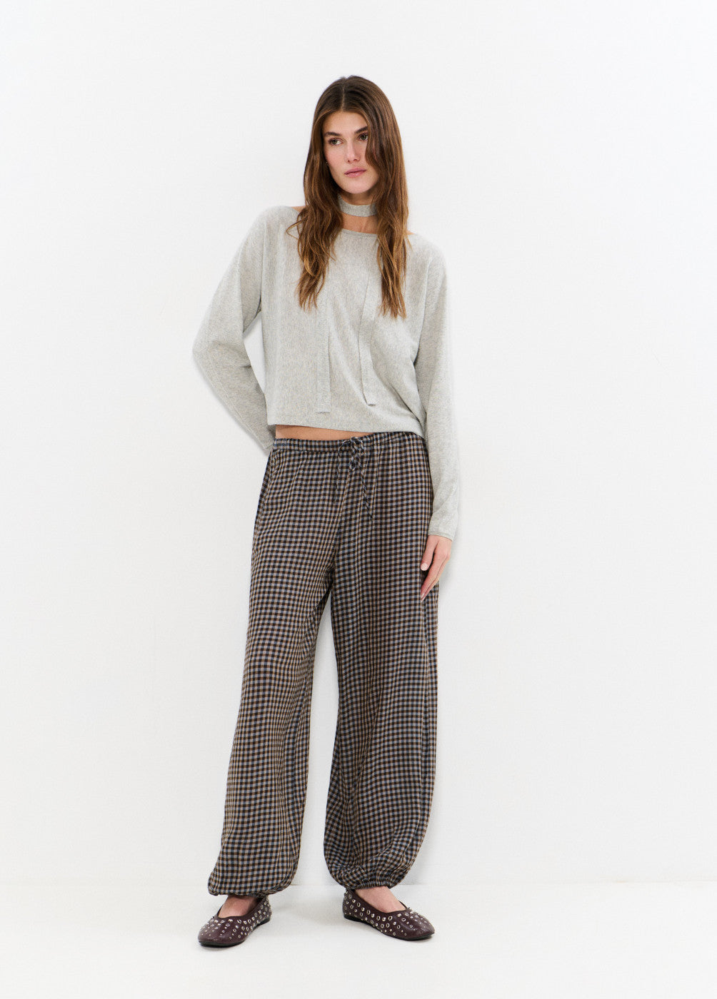 אישה עם סוודר אפור ומכנסיים רחבים משובצים, אופנת נשים סתיו חורף