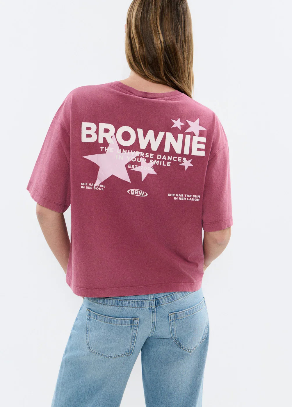 חולצת טי גזורה ורודה עם הדפס BROWNIE וכוכבים, נלבשת עם ג'ינס בהיר, מראה אופנתי לנשים