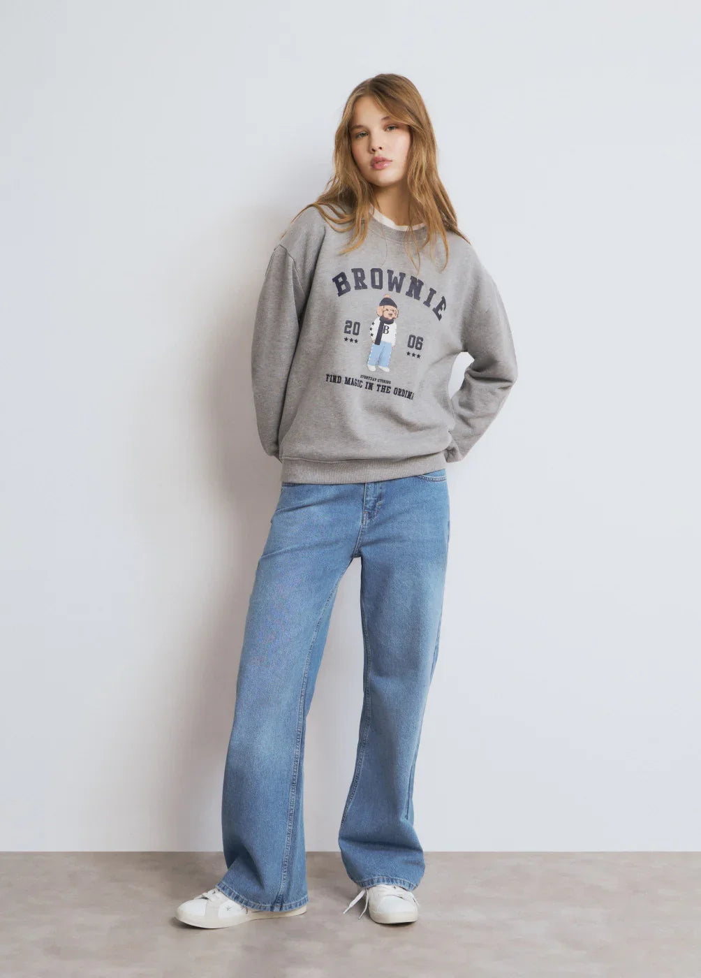 אישה לובשת סווטשירט אפור BROWNIE ומכנסי ג'ינס רחבים, אופנת רחוב טרנדי CHOZEN