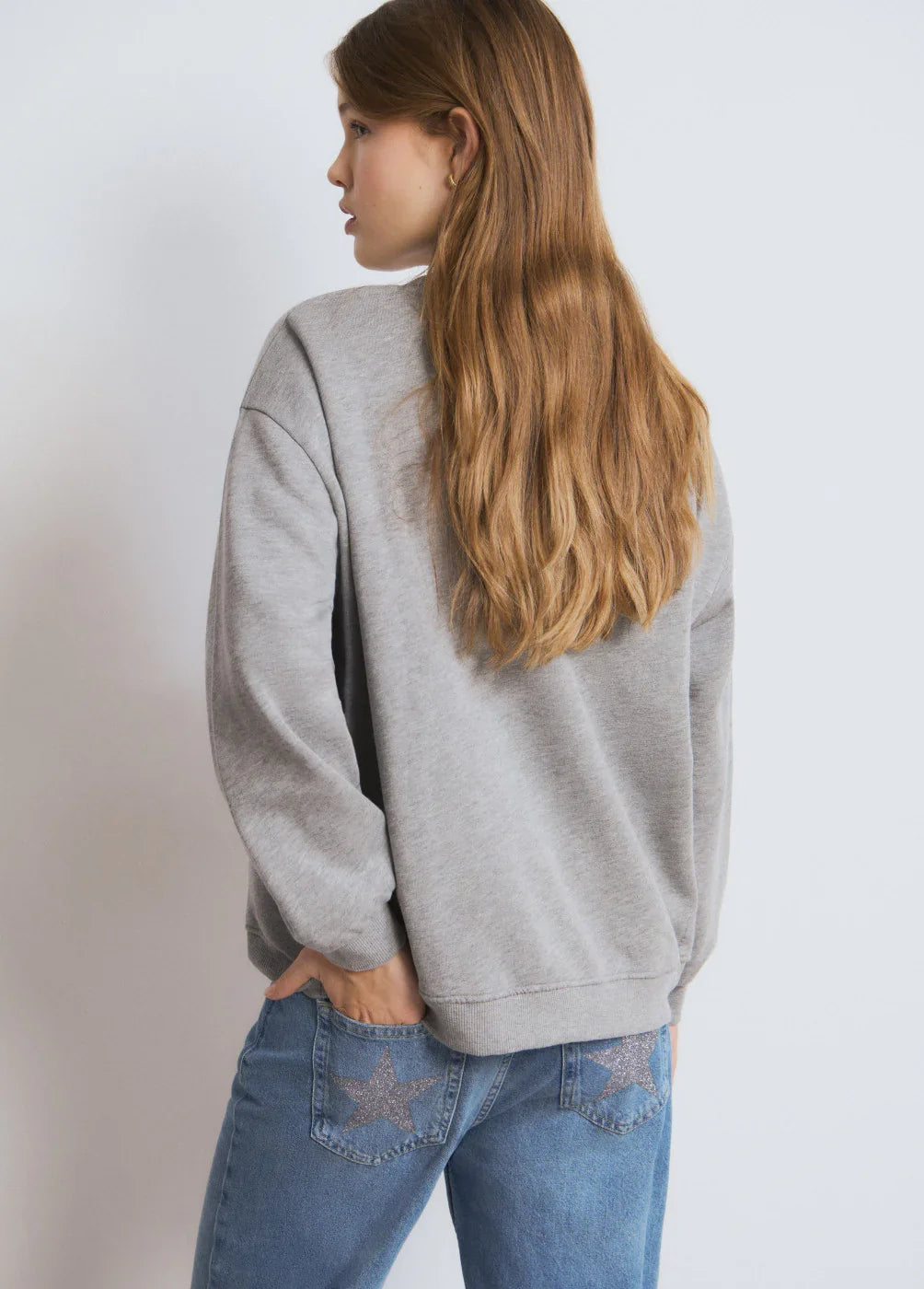 אישה עם סווטשירט אפור וג'ינס עם כוכבים על הכיסים, צילום אופנה CHOZEN