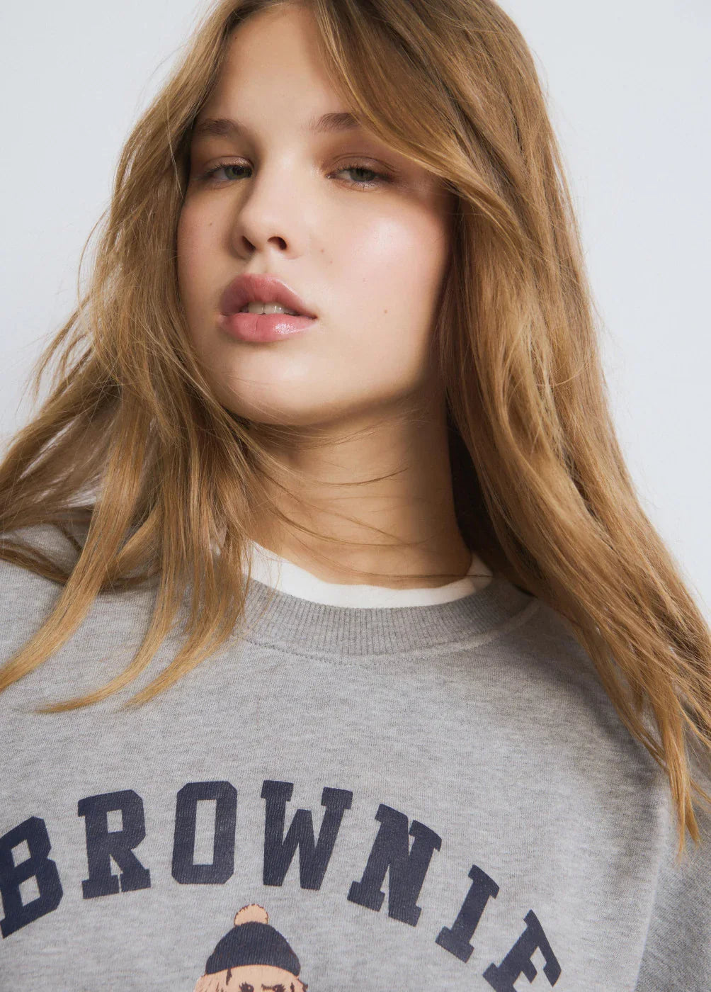 דוגמנית עם שיער בלונדיני לובשת סווטשירט אפור עם הדפס BROWNIE, צילום אופנה CHOZEN