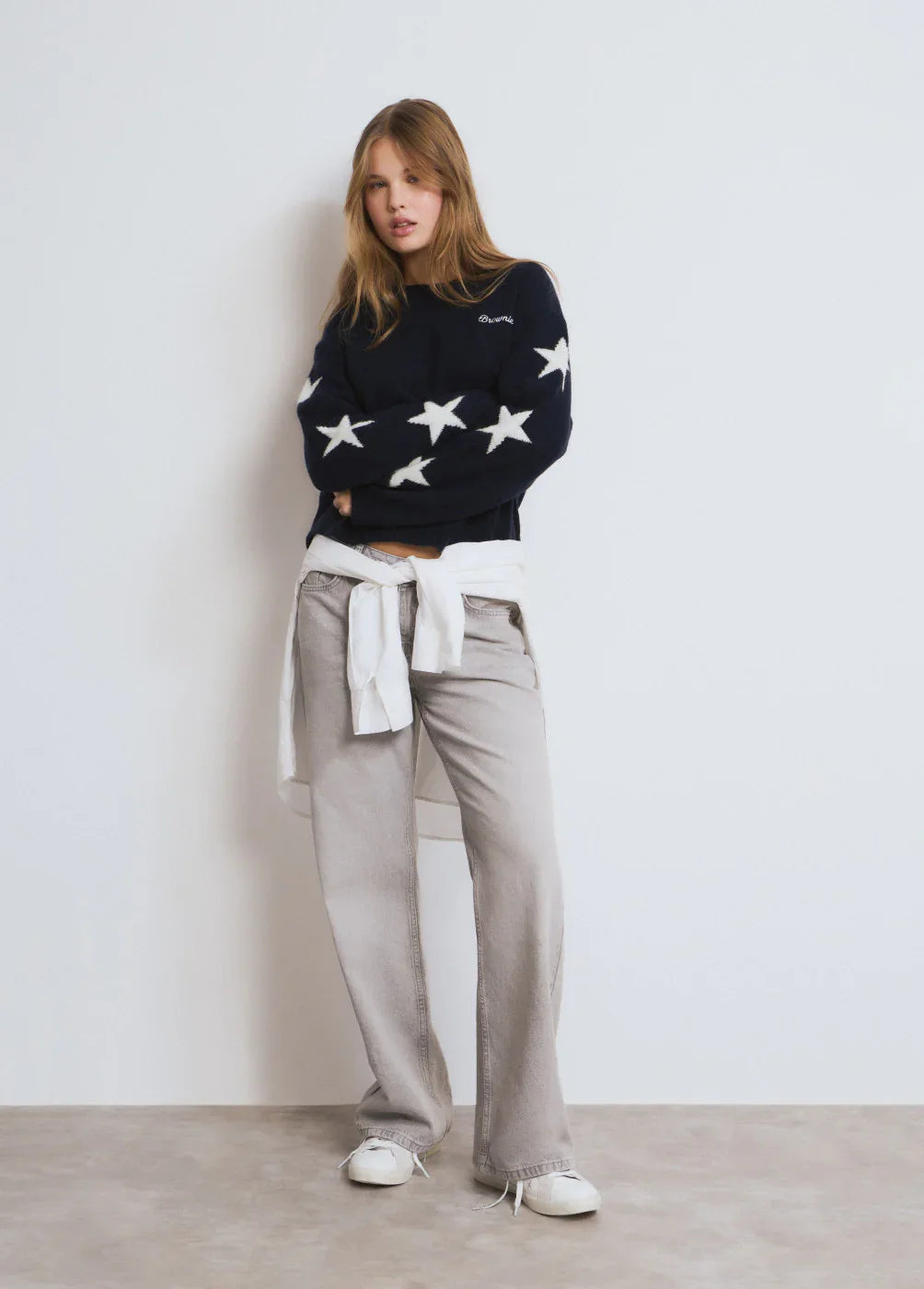 דוגמנית בסטייל קז'ואל עם סווטשרט כחול כהה עם כוכבים לבנים, מכנסיים אפורים נעליים לבנות, צילום לאתר CHOZEN