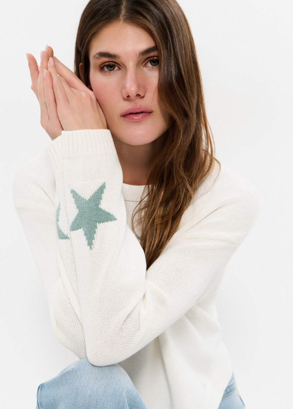 דוגמנית לובשת סוודר לבן עם כוכב טורקיז בשרוול, בגדי חורף אופנתיים לנשים