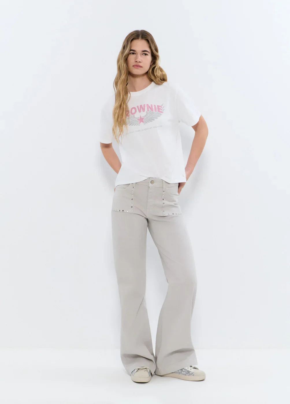 אישה עם חולצת טי שירט לבנה בהדפס ורוד ומכנסיים רחבים בהירים, אופנה קז'ואל מודרני