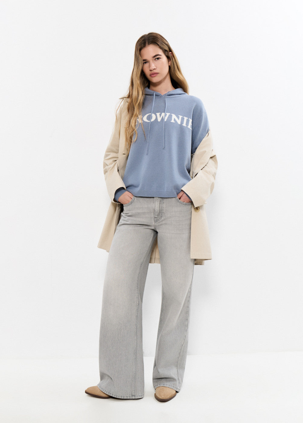 אישה לובשת סווטשרט כחול עם כיתוב, מעיל בז', וג'ינס אפור רחב, אופנת קז'ואל עדכנית