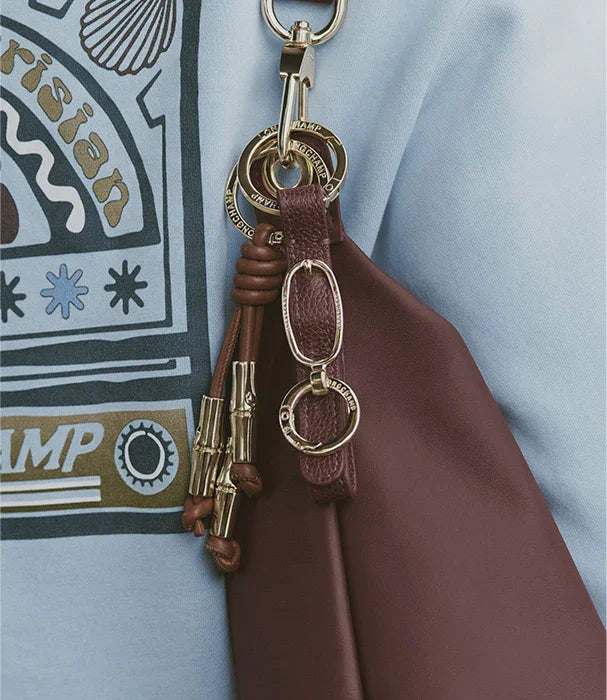 תקריב תיק עור חום עם קישוטי מתכת זהב על רקע חולצה תכלת, CHOZEN מותגים מובילים