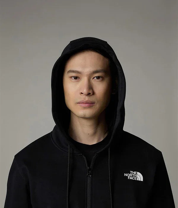 גבר עם קפוצ׳ון שחור של The North Face, מבט רציני, צילום אולפן, אופנת חורף מותגים