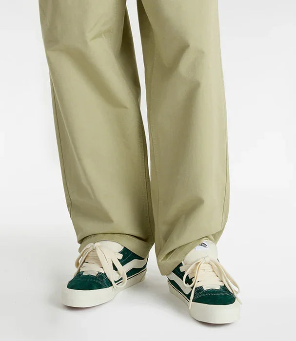 נעלי סניקרס ירוקות ולבנות עם לוגו, על רקע מכנסיים בהירות, בלעדי CHOZEN מותגים מובילים