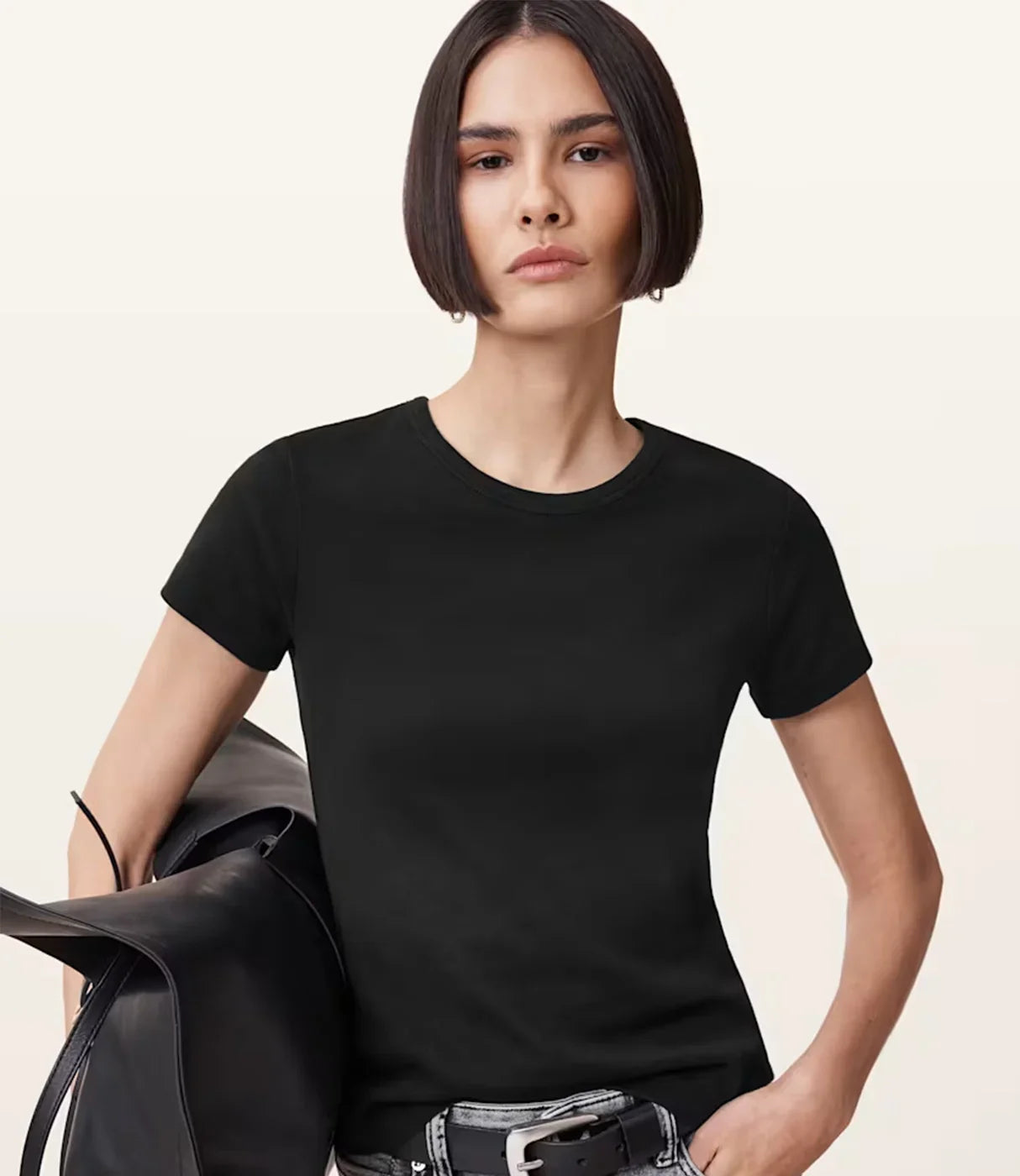 אישה לובשת חולצה שחורה קצרה ומחזיקה תיק עור שחור, סטייל אופנתי לנשים