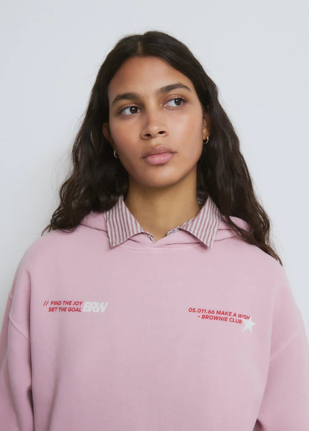 אישה לובשת סווטשירט ורוד עם כיתוב אדום ולבן, חולצת פסים מתחת, אופנה טרנדית CHOZEN