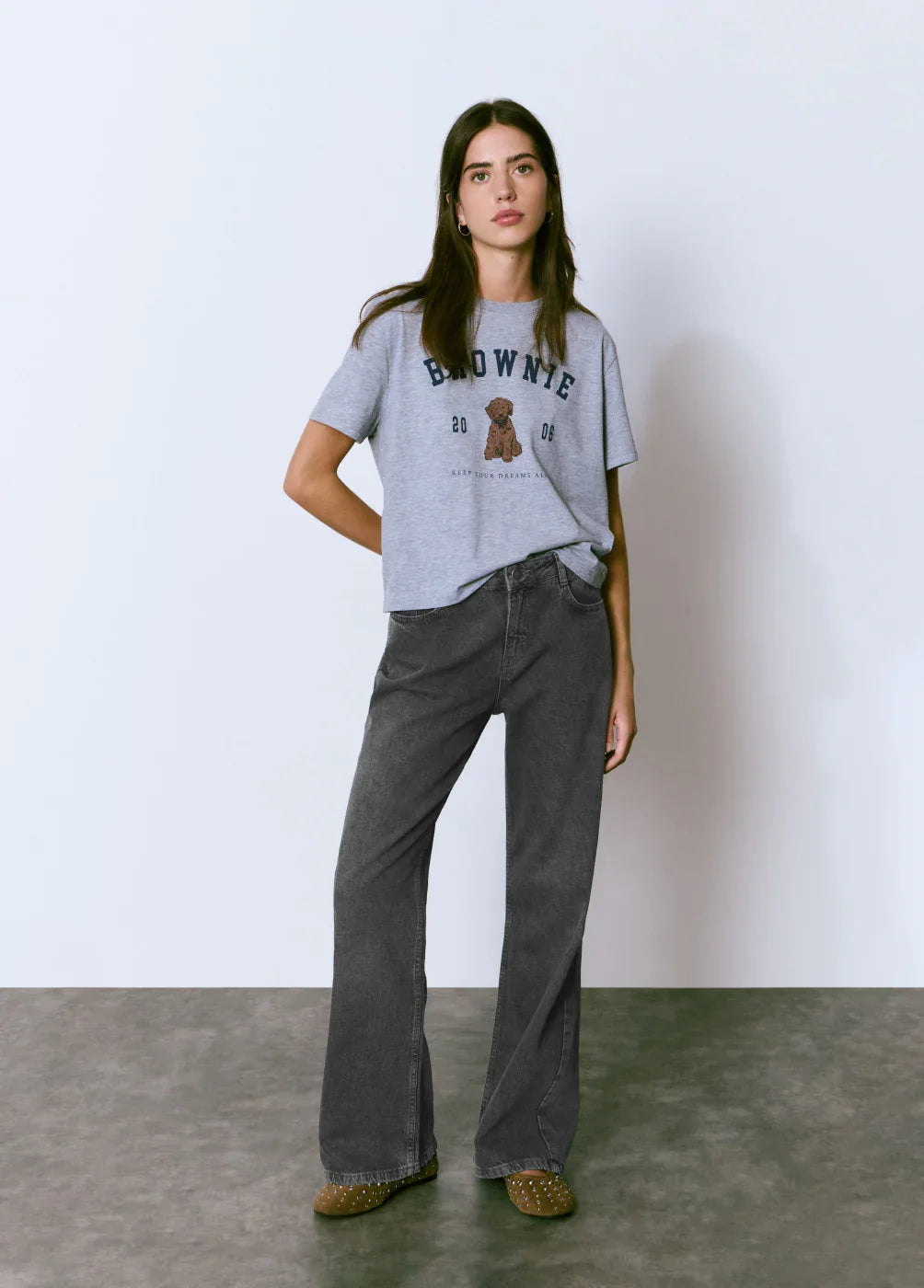 אישה לובשת חולצת טי אפורה עם הדפס דובי ומכנסיים שחורים, אופנה CHOZEN