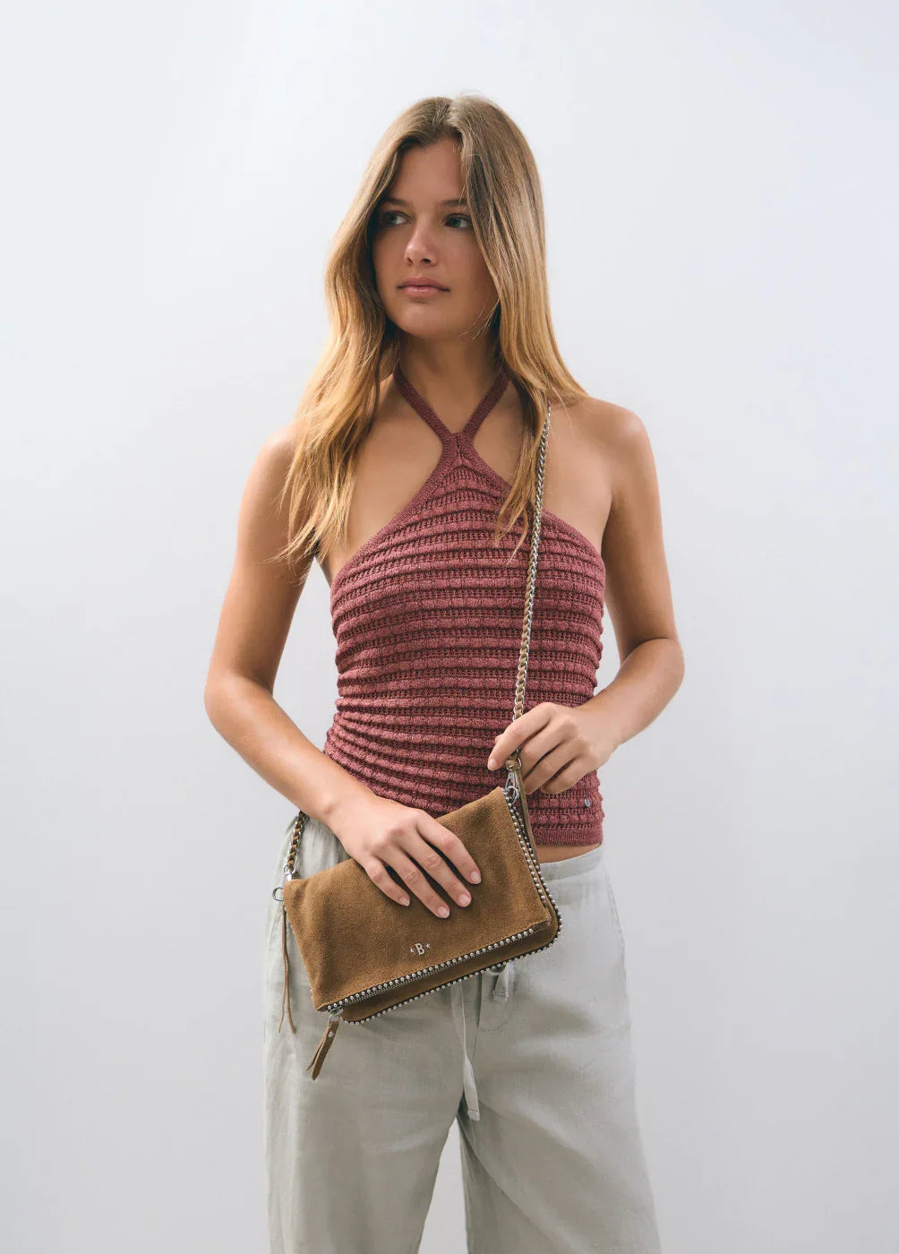 אישה עם גופיית קיץ סרוגה ורודה, תיק כתף חום ואופנה מודרנית מבית CHOZEN