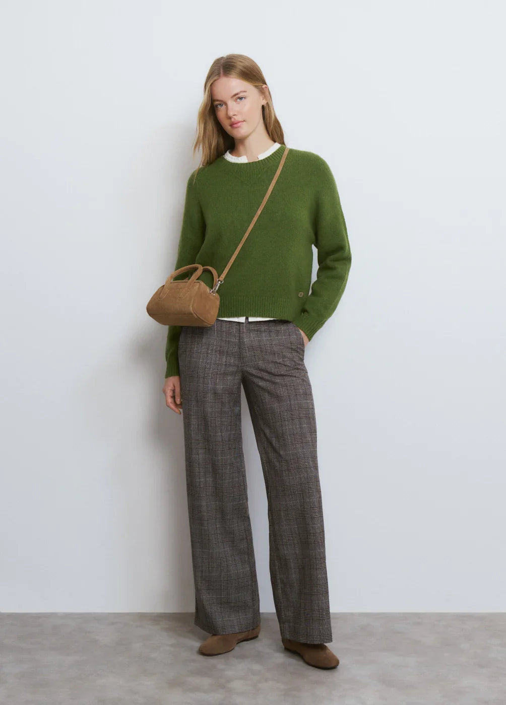 דוגמנית לובשת סוודר ירוק, מכנסיים משובצים ותיק צד חום, צילום אופנה של CHOZEN