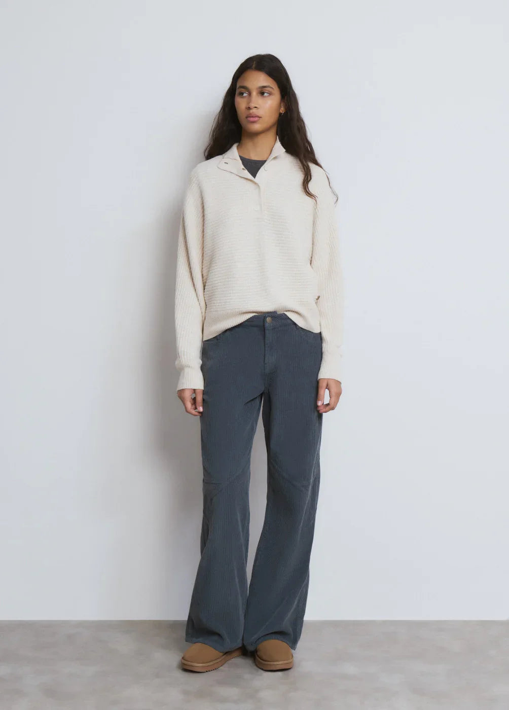 אישה בלבוש קז'ואל: סוודר שמנת, מכנסי קורדרוי כחולים ונעלי מוקסין חומות מצולמת על רקע לבן, אופנה באתר CHOZEN