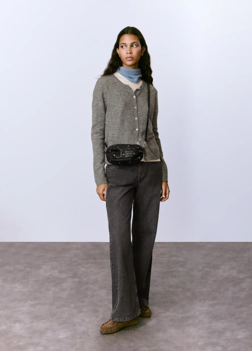 אישה בסטייל קז'ואל עם סוודר אפור, צעיף כחול, מכנסיים כהים ותיק צד שחור, CHOZEN אופנה