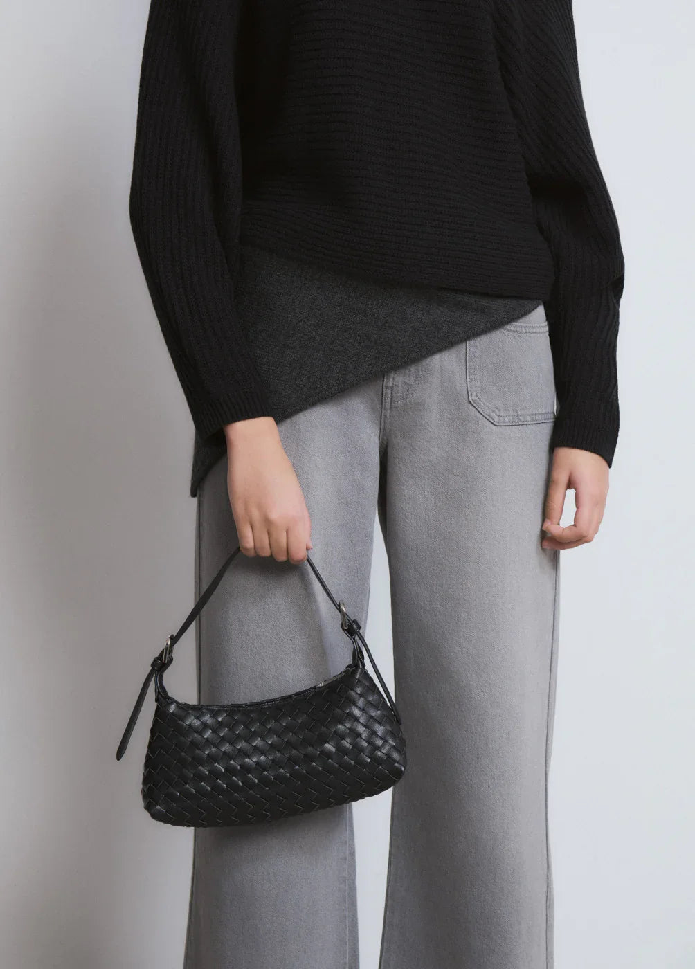 אישה בלבוש קז'ואל מחזיקה תיק כתף קלוע שחור, אופנה באתר CHOZEN