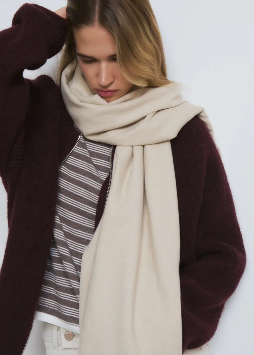 אישה עם צעיף בז' גדול, סוודר בורדו וחולצה מפוספסת מבית CHOZEN