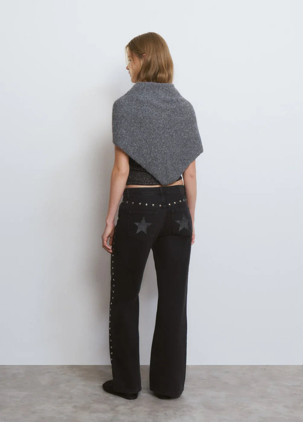 דגם CHOZEN: אישה עם שאל אפור, מכנסיים שחורים עם כוכבים, רקע לבן