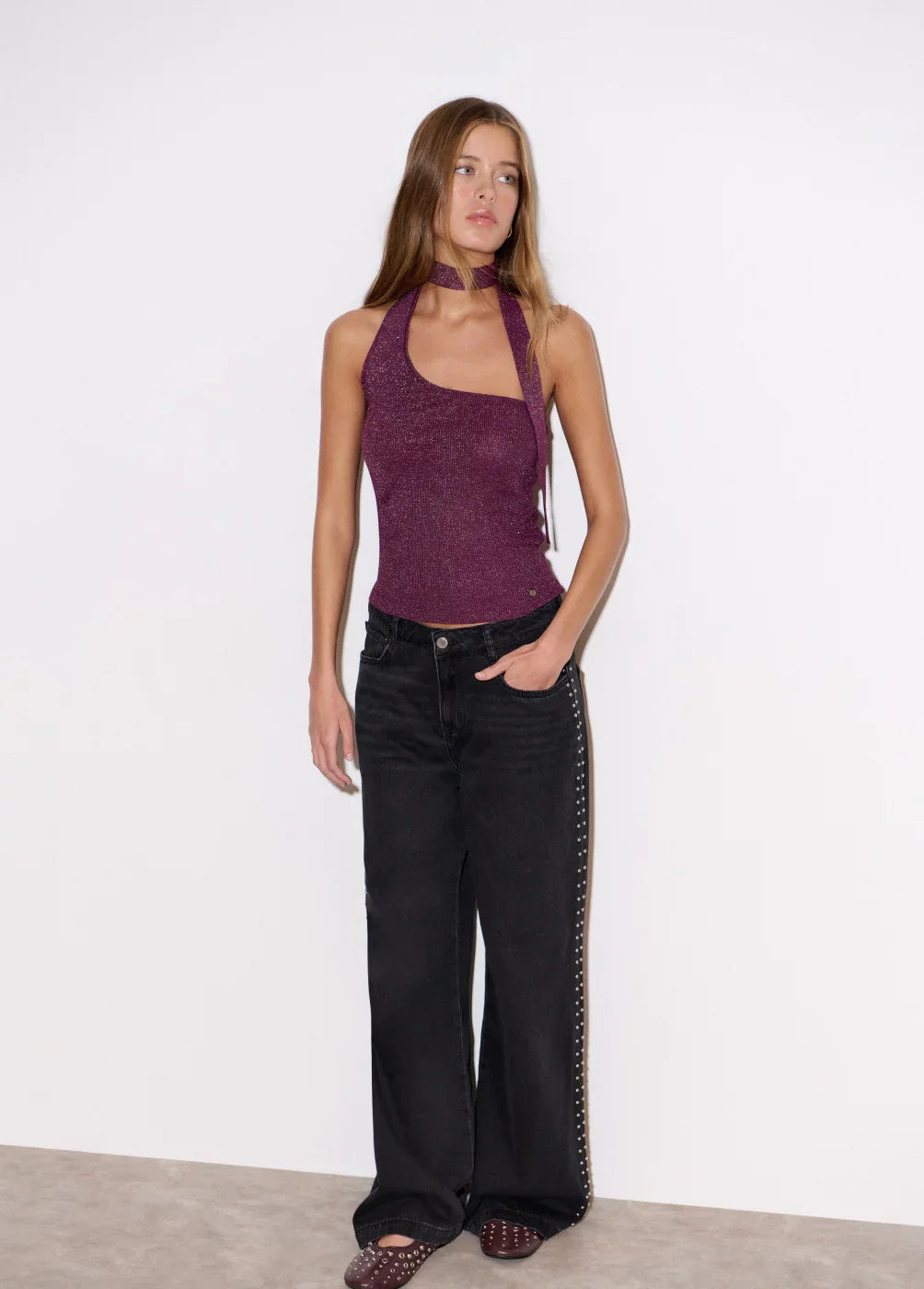 אישה לובשת גופיה סגולה מבריקה ומכנסיים שחורים עם ניטים, אופנת נשים CHOZEN