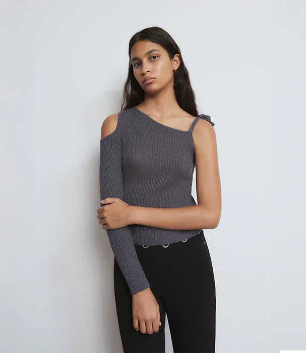 דוגמנית לובשת חולצת כתף אחת כהה ואופנתית ומכנסיים שחורים, צילום לאתר CHOZEN