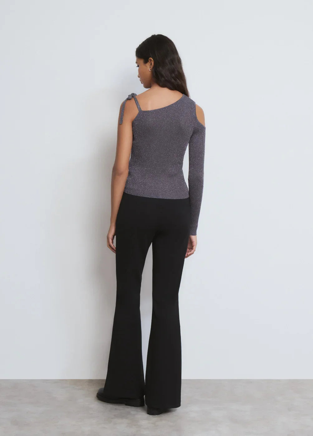 דוגמנית עם חולצה סרוגה מנצנצת עם כתף חשופה ומכנסיים שחורים אלגנטיים, CHOZEN