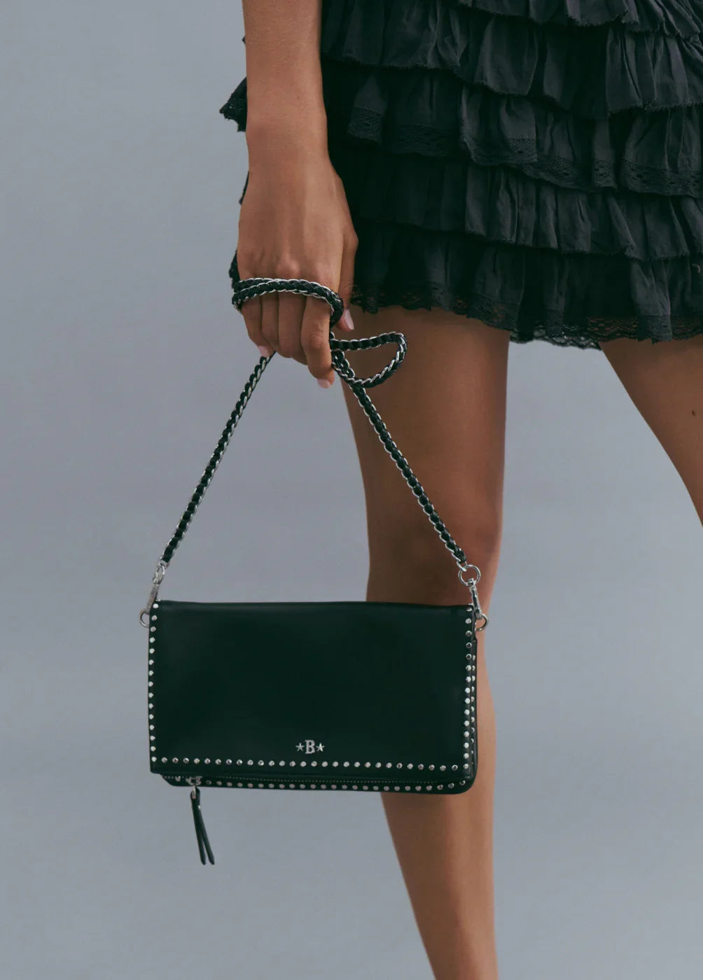 תיק קלאץ' שחור עם ניטים כסופים, רצועת יד קלועה, אופנת CHOZEN ביבוא קבוצת אלפא