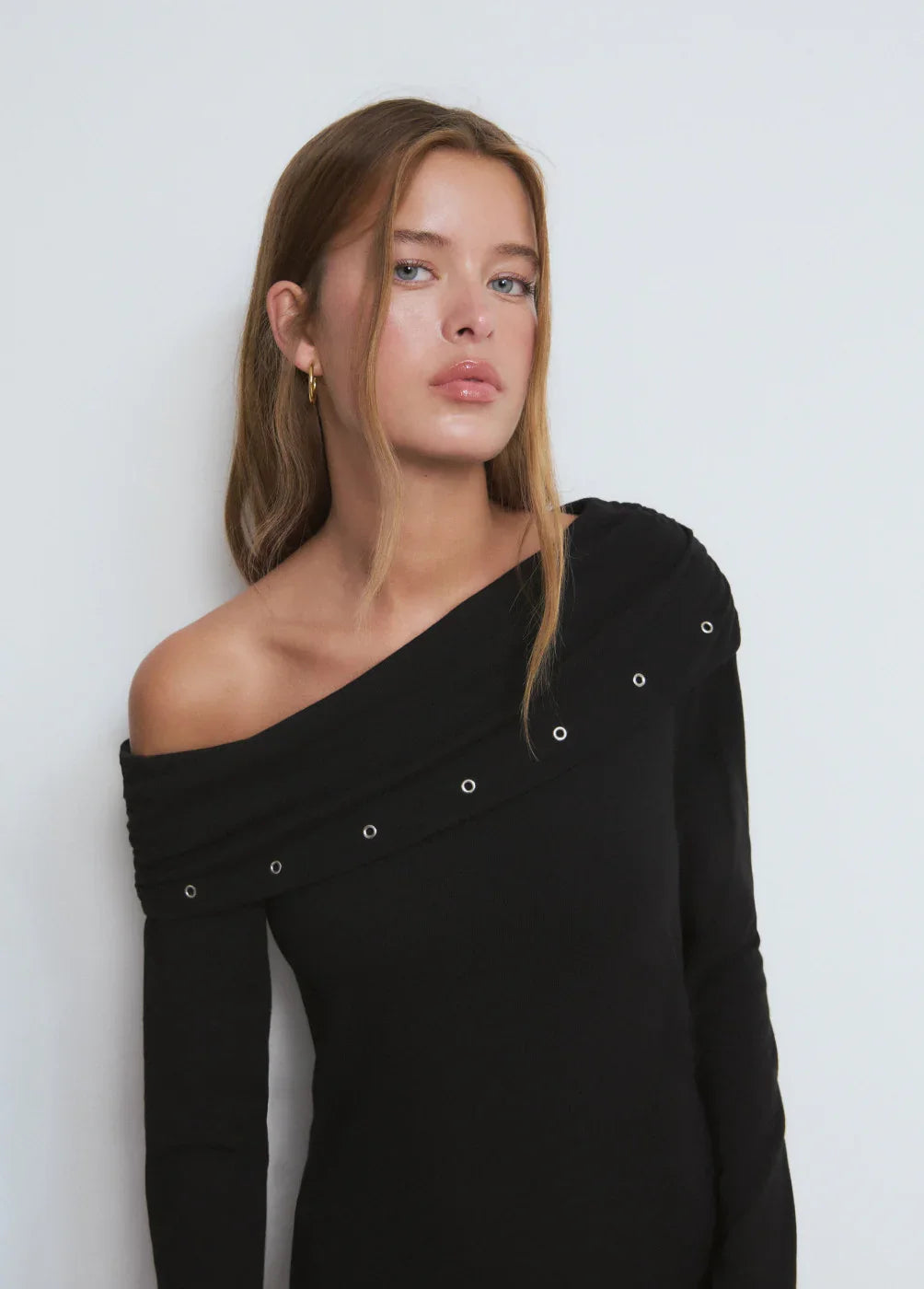 דוגמנית עם שיער בלונדיני לובשת חולצת כתף אחת שחורה עם ניטים, צילומי אופנה CHOZEN